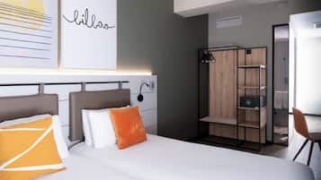 A modern hotel room with a large bed, a wardrobe, and a desk.