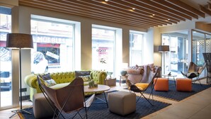 A modern lobby with a green sofa, armchairs, and ottomans.