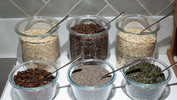 Five glass jars containing different grains and seeds on a kitchen counter.