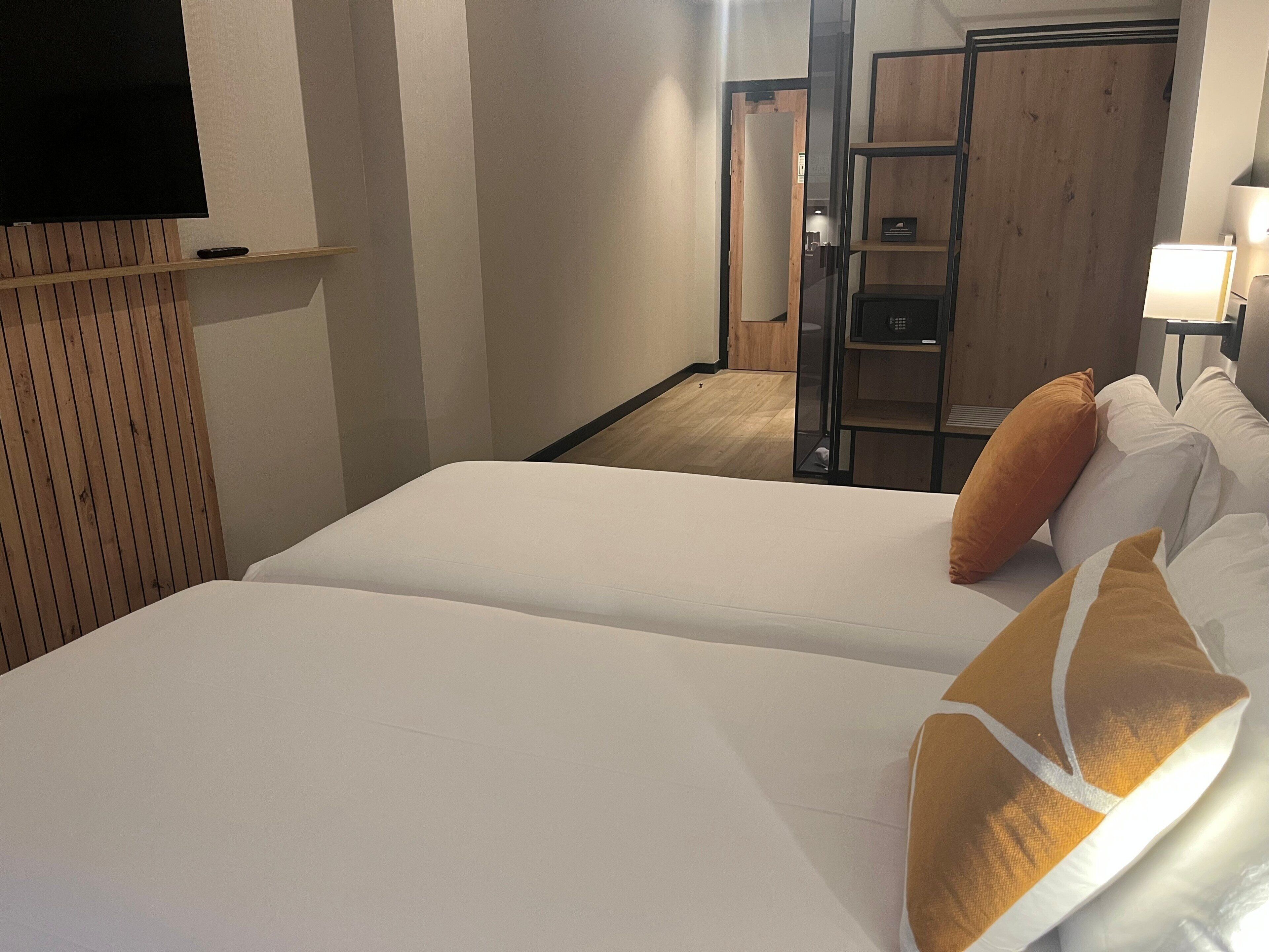 Une chambre d’hôtel avec un lit, des oreillers, une télévision et une armoire en bois.