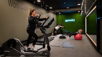 Una palestra con tapis roulant, una palla da ginnastica e un neon che riporta la scritta "gym4U".