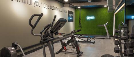 A gym with exercise equipment, a motivational quote on the wall, and a green wall with a 'gym' sign.