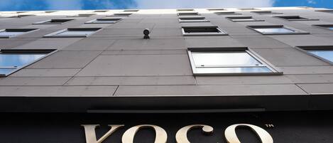 Fachada de edificio con el letrero "Voco by IHG", que indica un hotel.