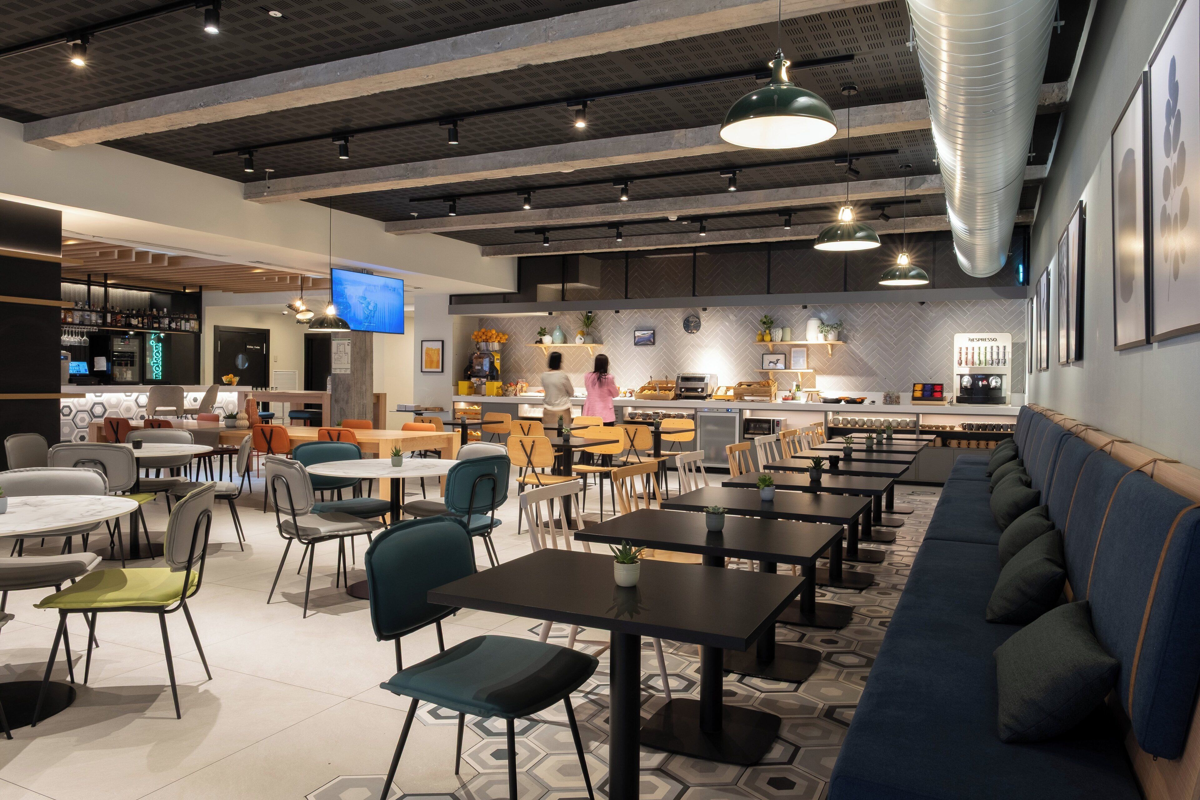 A modern cafe interior with multiple seating options, a kitchen area, and a bar.