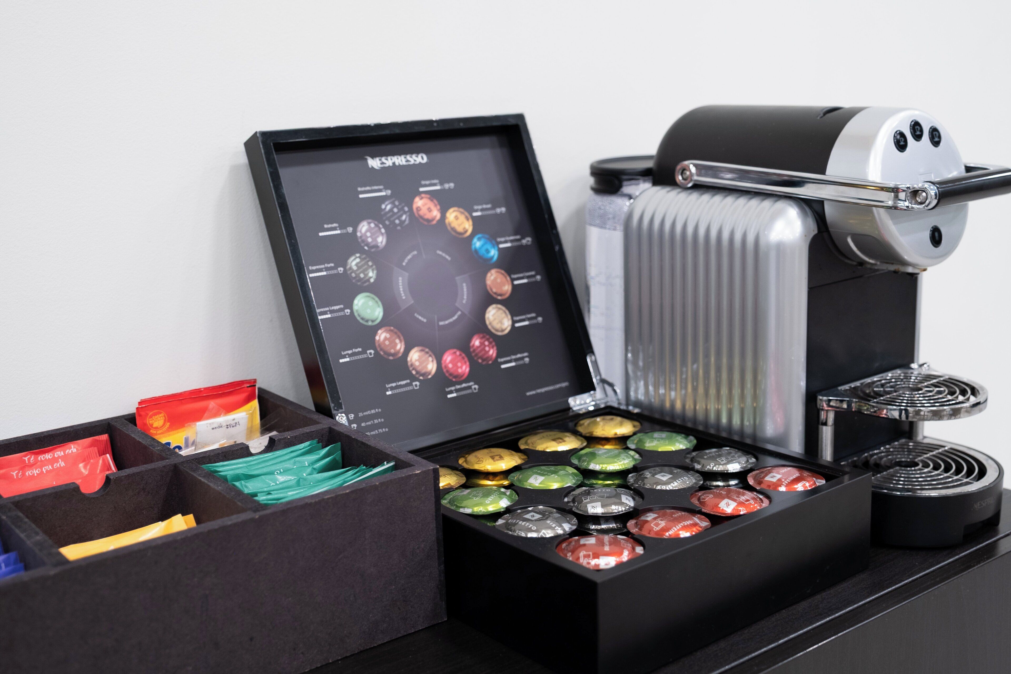 A coffee machine with a display panel and a box of coffee capsules.