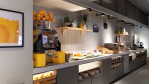 A modern breakfast bar with a variety of food items, including fruits, pastries, and beverages.