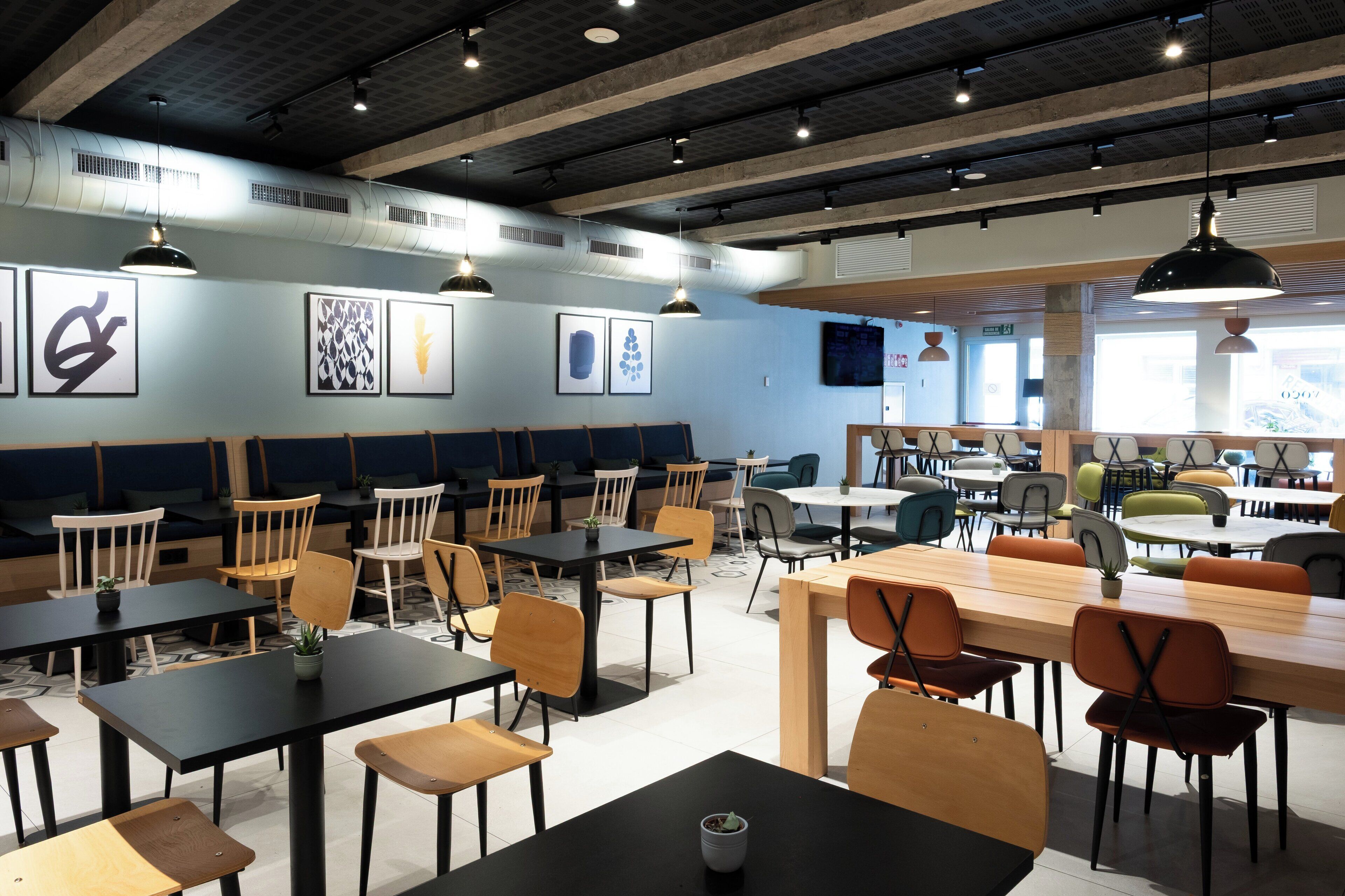 A modern restaurant with multiple seating areas, including booths and tables, and a variety of chairs.
