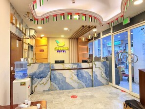Un espace d’accueil d’hôtel avec un comptoir en marbre, un distributeur d’eau et un bureau de réception.