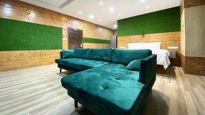 Une chambre d’hôtel moderne avec un canapé vert, un lit et un mur décoratif en bois.