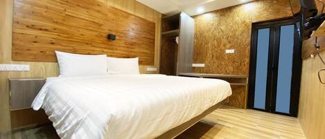 A hotel room with a large bed, wooden paneling on the walls, a mirror, and a door with a blue frame.