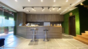 Une cuisine moderne dotée d’un îlot central, de deux tabourets de bar et d’un mur d’accent vert.