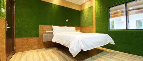 Una habitación con una cama, una mesita de noche, una lámpara de pared y una ventana.