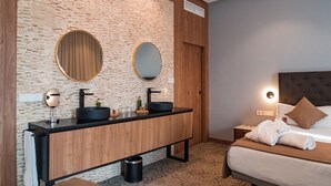 A modern hotel room with a wooden vanity, two round mirrors, a black sink, and a bed with a brown headboard. - Hotel AJ Gran Alacant (Santa Pola)