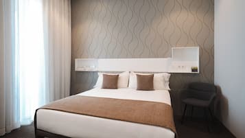 Habitación de hotel con una cama grande, una silla, una mesita de noche y un estante en la pared.