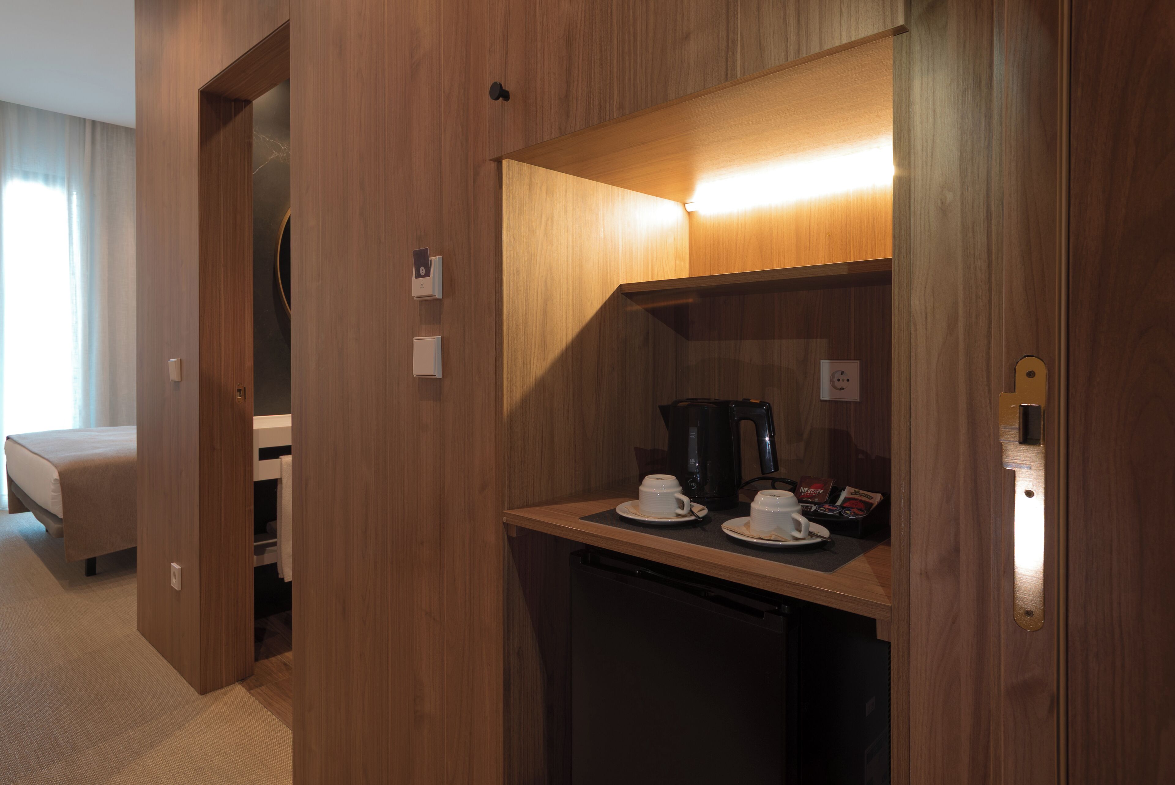 Habitación de hotel compacta con kitchenette, una cama y una pequeña zona de estar.