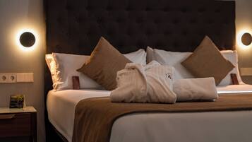 Una habitación de hotel con una cama grande, dos almohadas, una mesita de noche con lámpara y una lámpara de pared.