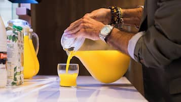 Una persona vertiendo jugo de naranja en un vaso.