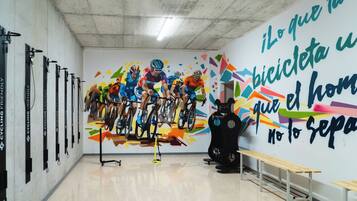A gym with a mural of cyclists, exercise equipment, and benches.