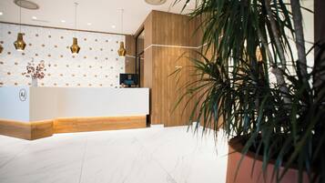 A reception area with a wooden reception desk, marble flooring, and a patterned wall.