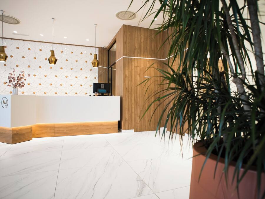 A reception area with a wooden reception desk, marble flooring, and a patterned wall.