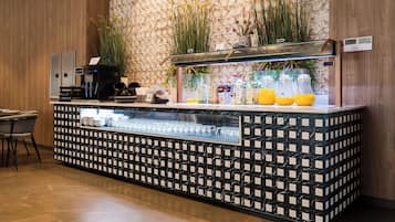A bar area with a patterned counter, a coffee machine, and a glass display case.
