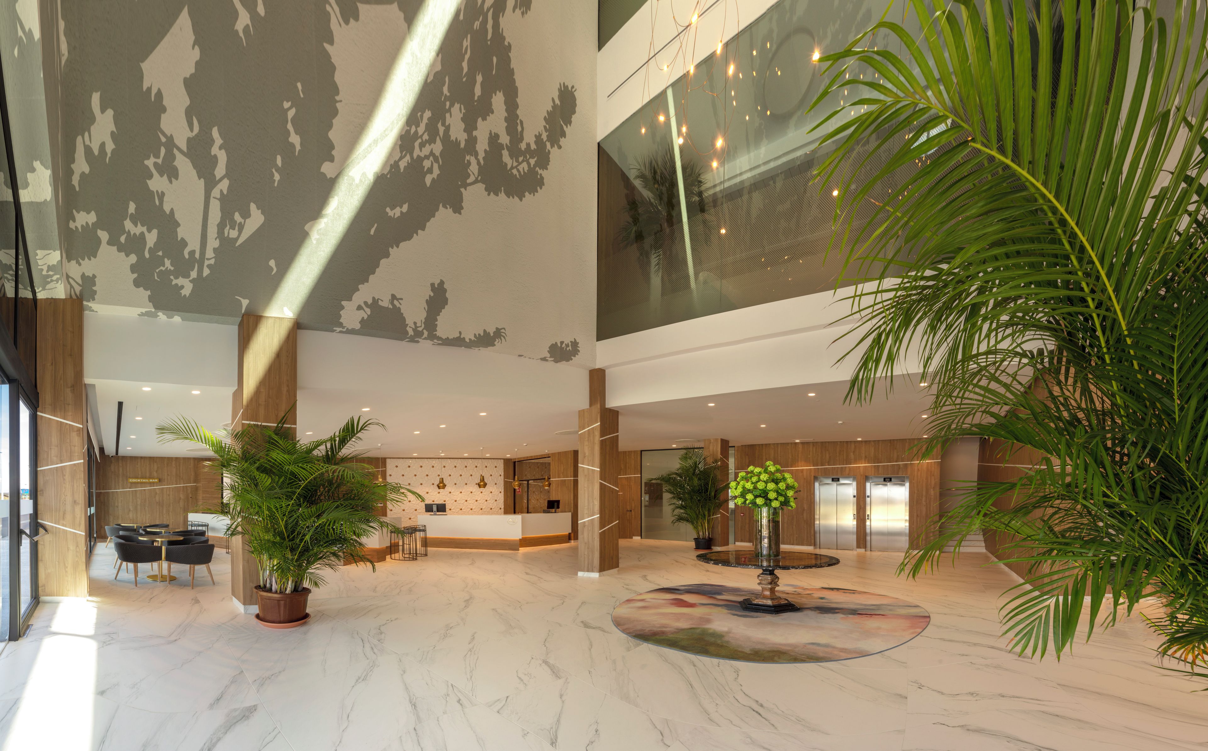 A spacious lobby with a high ceiling, marble flooring, and a central decorative feature.