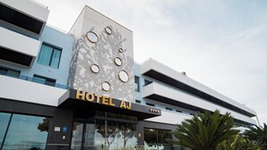 A modern hotel with a prominent sign reading "HOTEL AJ" and a facade featuring circular windows and a patterned wall. - Hotel AJ Gran Alacant (Santa Pola)