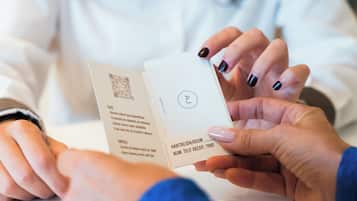 A person holding a hotel card with a QR code and text indicating room number 7000.