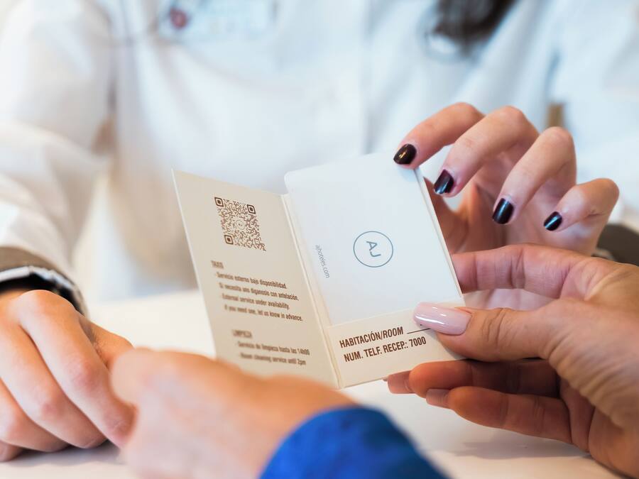 A person holding a hotel card with a QR code and text indicating room number 7000.
