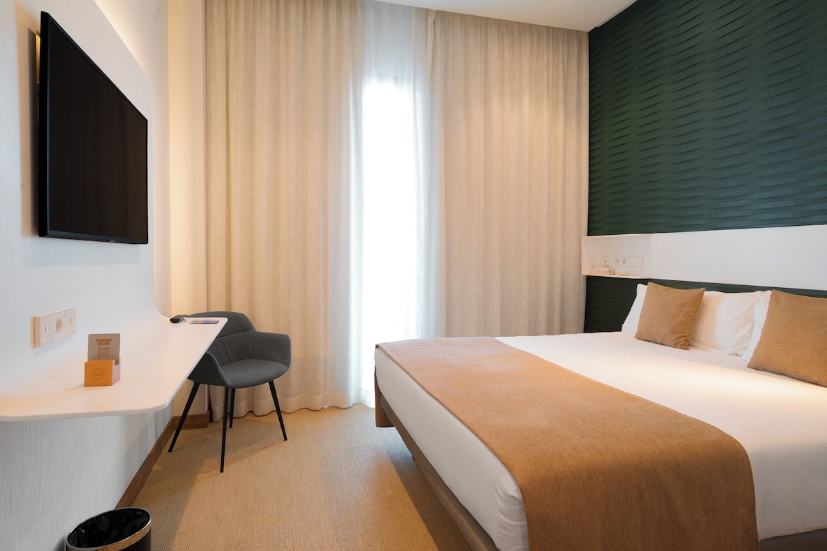 Una habitación de hotel con una cama, un escritorio y una silla.