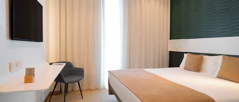 A hotel room with a bed, a desk, and a chair.