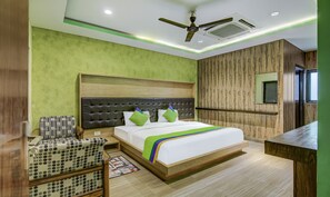 Ein Hotelzimmer mit Bett, Stuhl, Schreibtisch und Deckenventilator.