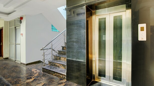 Um elevador moderno com portas de vidro e corrimão metálico.