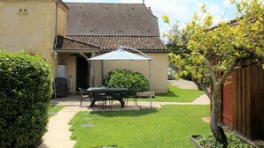 A house with a tiled roof, a covered patio with a table and chairs, and a well-maintained lawn. - Charming house in Lamonzie-Saint-Martin (Lamonzie-Saint-Martin)
