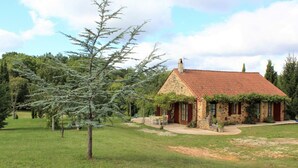 A stone house with a red-tiled roof, surrounded by a grassy lawn and trees. - Périgord house with fireplace near Monpazier (Mazeyrolles)