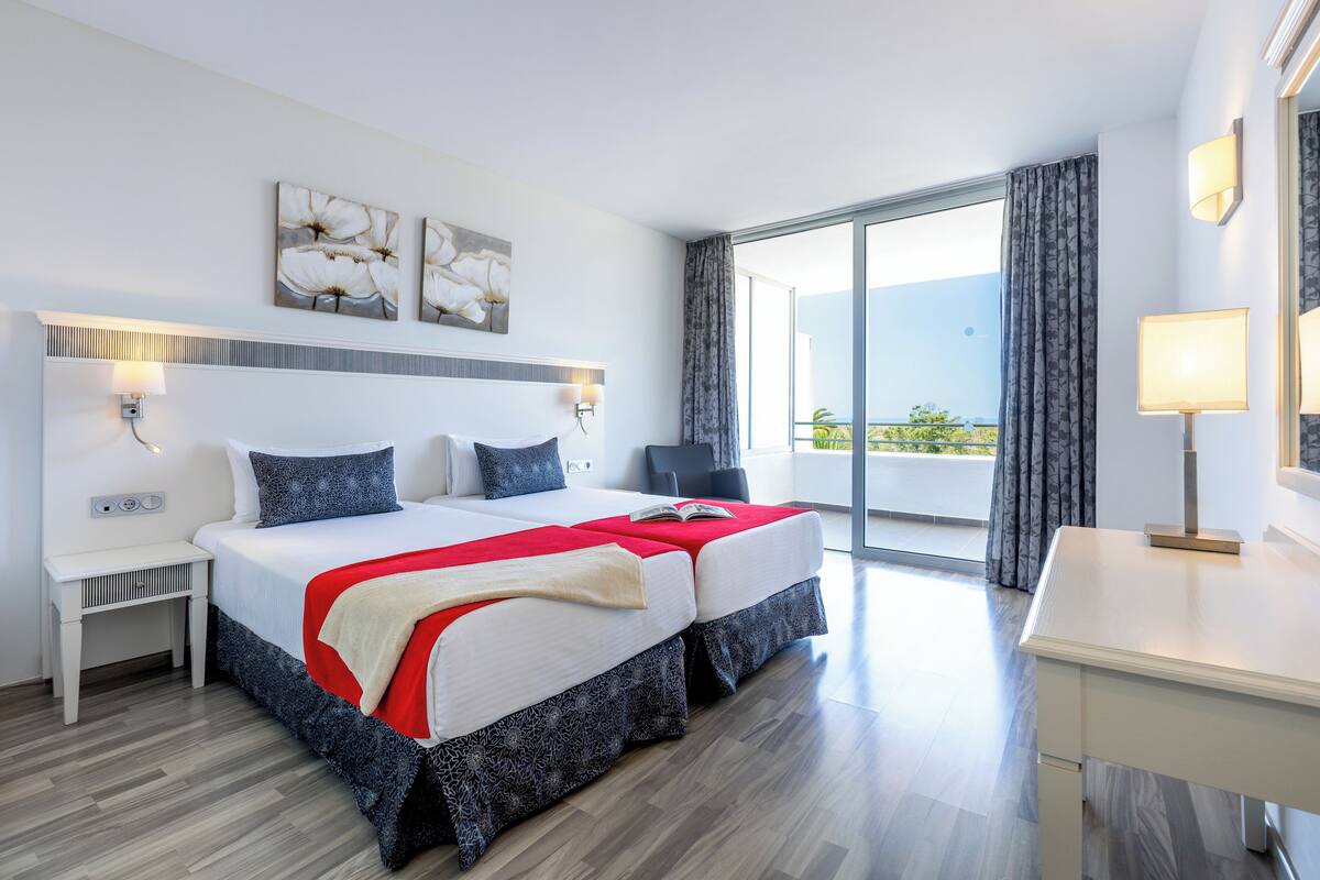 Une chambre d’hôtel avec un grand lit, un bureau, une chaise et un balcon avec vue.