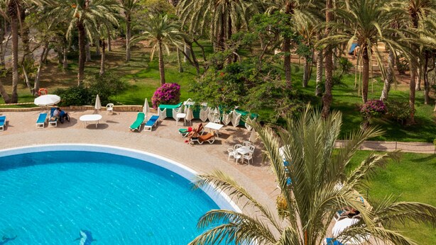 Ein Resort mit Swimmingpool, Palmen und Blick auf den Ozean.