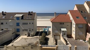 Un quartier résidentiel situé sur la côte, avec des bâtiments dotés de toits en tuiles et offrant une vue dégagée sur la plage.