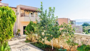 A residential building with a stone wall, a balcony, and a garden area with a table and chairs.