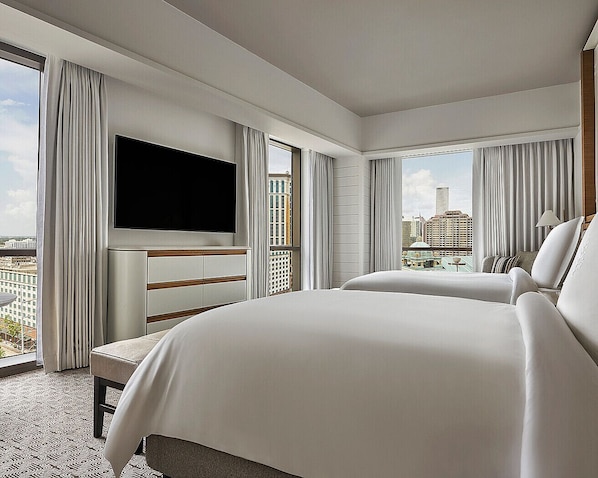 A hotel room with a large bed, a TV, and a view of the city.