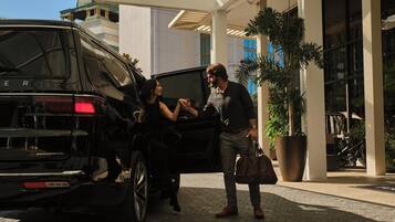 A black SUV parked outside a building with a large potted plant nearby.