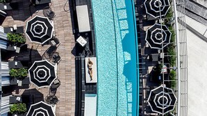 An aerial view of a rooftop pool area with multiple hexagonal umbrellas and lounge chairs.