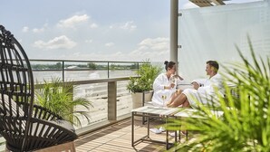 Ein Paar sitzt auf einem Balkon mit Blick auf einen Fluss.