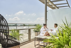 Una pareja sentada en un balcón con vistas a un río.