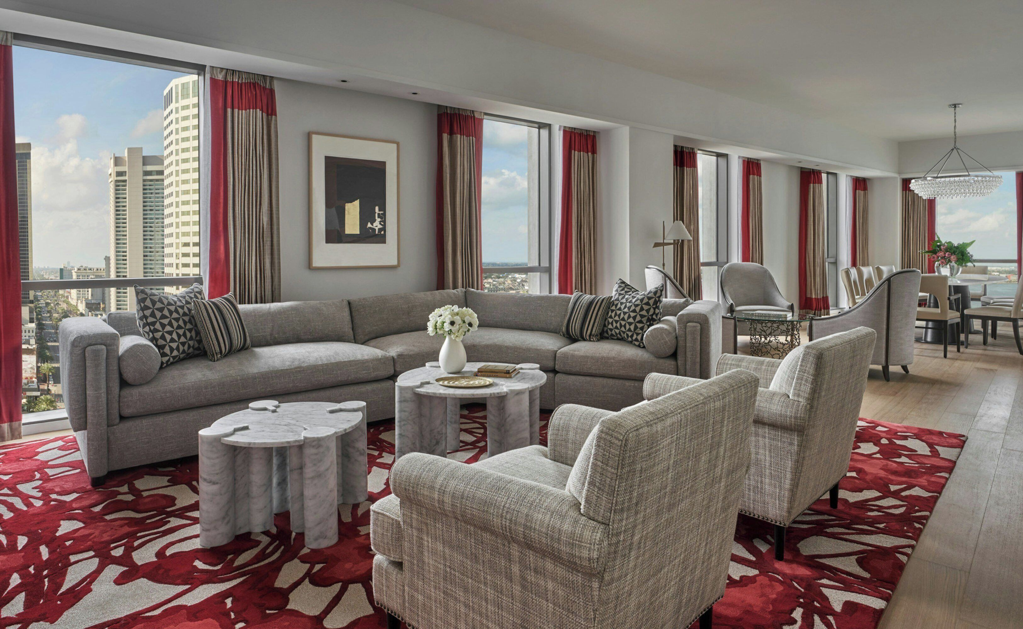 A modern living room with a grey sectional sofa, round coffee tables, and grey armchairs.