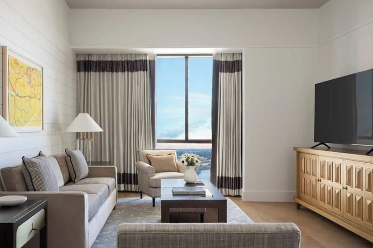 Ein modernes Wohnzimmer mit einer Couch, Sesseln, einem Couchtisch und einem Fernseher.