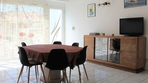 A dining area with a table and chairs, a cabinet with a television, and artwork on the wall.