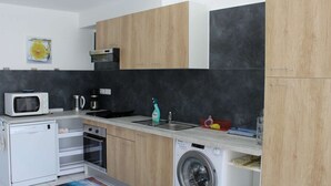 A compact kitchen with a microwave, coffee maker, sink, and washing machine.