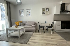 En modern lägenhet med vardagsrum, matbord och ett litet kök.