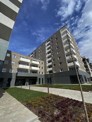 A modern multi-story building with a flat roof, large windows, and a central courtyard.